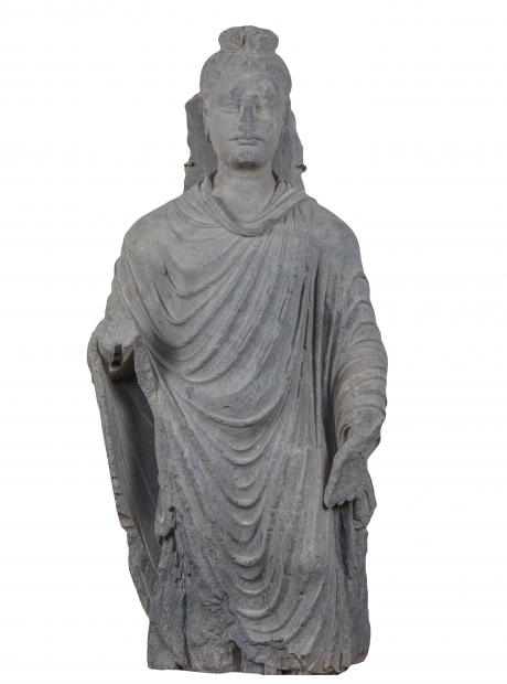 <h3>Buddha in Attitude of Reassurance</h3> <p>Grey schist<br /> 2nd – 3rd Century CE.<br /> Dharmarajika<br /> 95 x 45 x 17cm<br /> A stone sculpture of the standing Buddha, clad in a simple monastic robe. The drapery folds and the wavy hair are naturalistically carved. The hair culminates in a topknot visually symbolizing the ushnisha, one of the attributes (laksanas) of a transcendental being. The Buddha is depicted in a ritual gesture of reassurance (abhaya-mudra).</p>